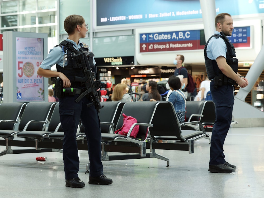 Eine Bundespolizistin und ein Bundespolizist stehen im Flughafen Düsseldorf.