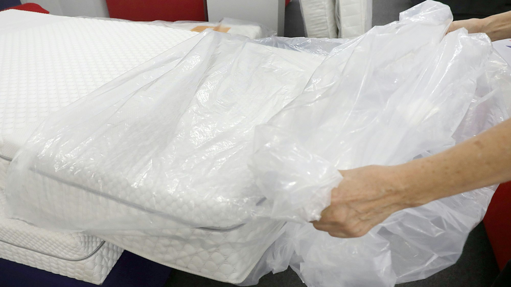 Eine Frau packt eine neue Matratze aus der Verpackungsfolie aus.