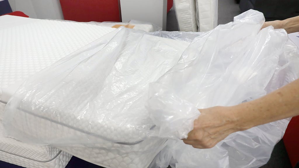 Eine Frau packt eine neue Matratze aus der Verpackungsfolie aus.&nbsp;