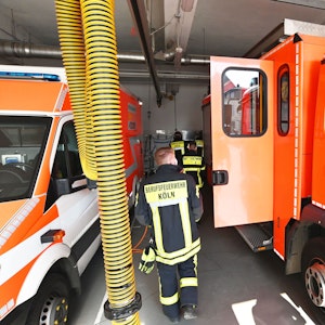 Einsatzkräfte der Feuerwehr Köln laufen an Einsatzfahrzeugen vorbei.