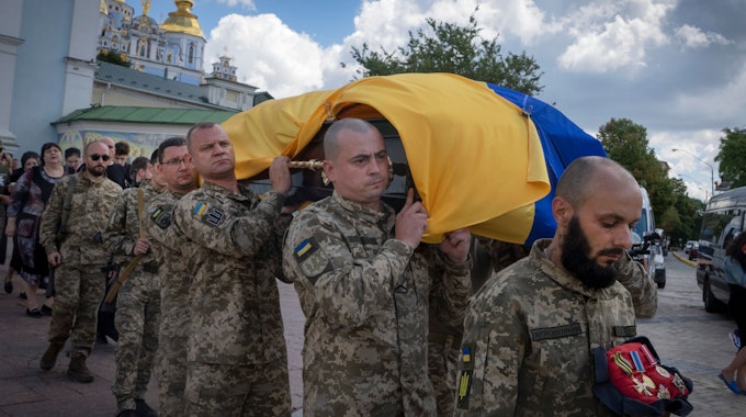 Soldaten aus der Ukraine tragen in Kyjw den Sarg eines gefallenen Kollegen. Auf dem Sarg liegt die ukrainische Landesflagge.