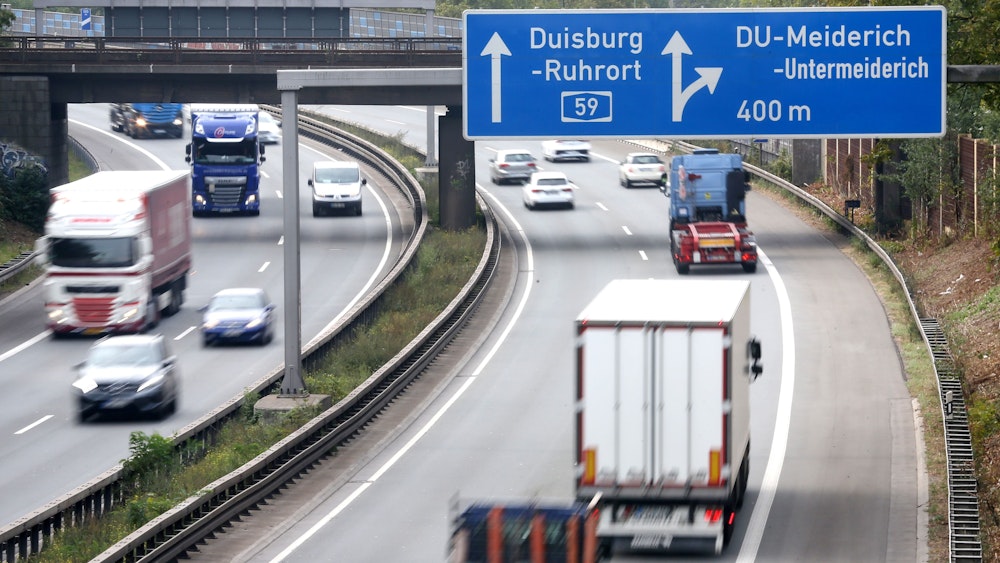 Autos fahren unter einem Autobahnschild auf der A59 bei Duisburg durch.