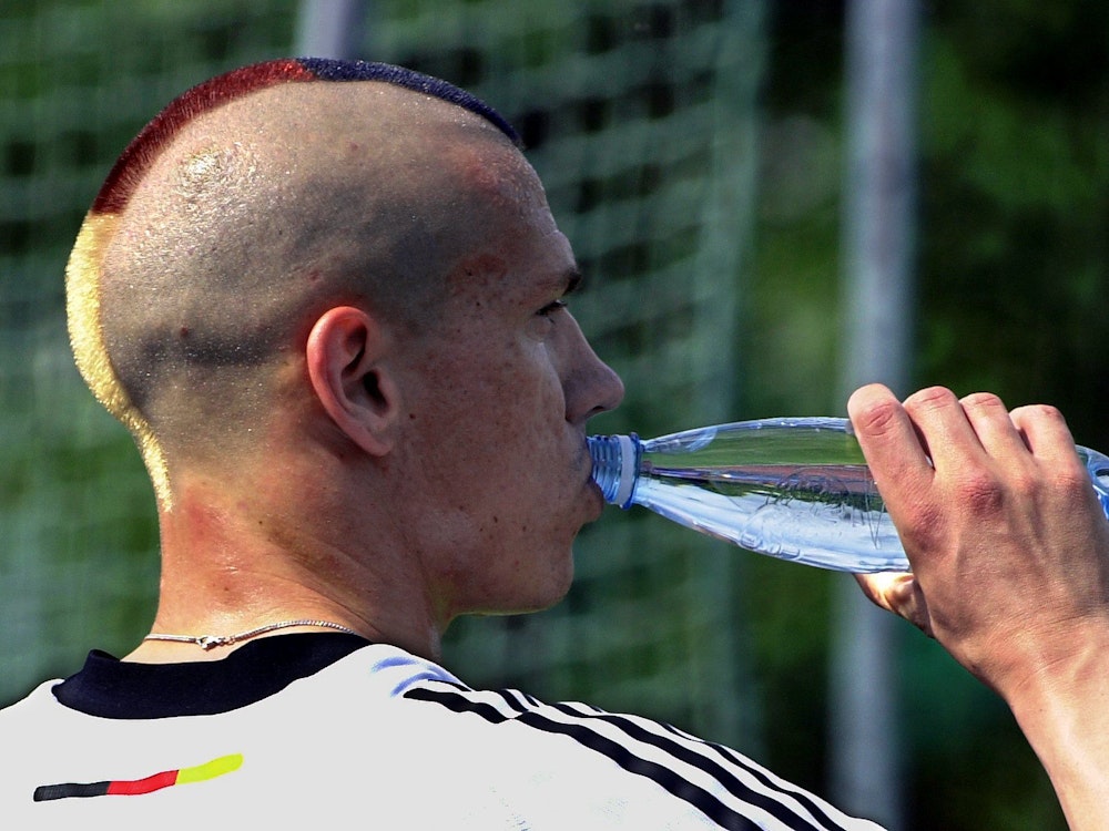 Christian Ziege mit frischem Irokesen-Haarschnitt in den Nationalfarben nimmt einen Schluck aus seiner Wasserflasche.