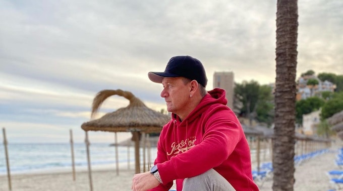 Der verstorbene Mallorca-Sänger Alex Zapata sitzt auf einem Mäuerchen am Strand .Das Foto postete er im April 2021 auf seinem Instagram-Profil.