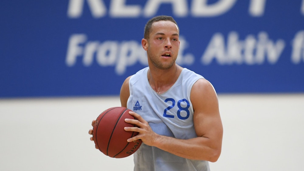 Andrej Mangold im Basketball-Trikot beim Training des Bundesligisten Fraport Skyliners mit Ball in der Hand