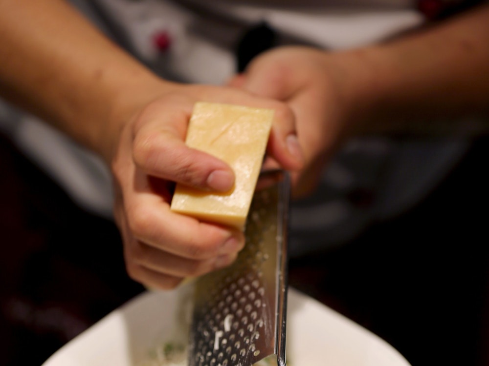 Ein Köchin reibt in einer Filiale der Restaurantkette Vapiano Parmesan auf ein Pasta-Gericht.