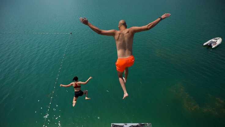 Zwei Menschen springen in Bosnien in einen See.
