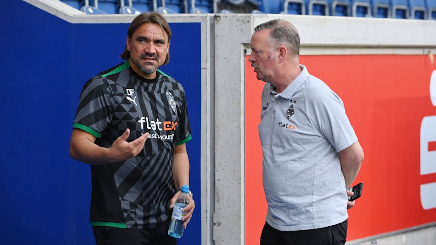 Trainer Daniel Farke von Borussia Mönchengladbach am 17. Juli 2022 in Duisburg im Gespräch mit Sportdirektor Roland Virkus. Farke gestikuliert mit der rechten Hand, Virkus hat die Arme hinter dem Rücken verschränkt.