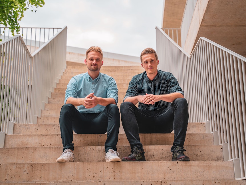 Die NeoTaste-Gründer Tobias Düser und Hendrik Sander sitzen auf einer Treppe.
