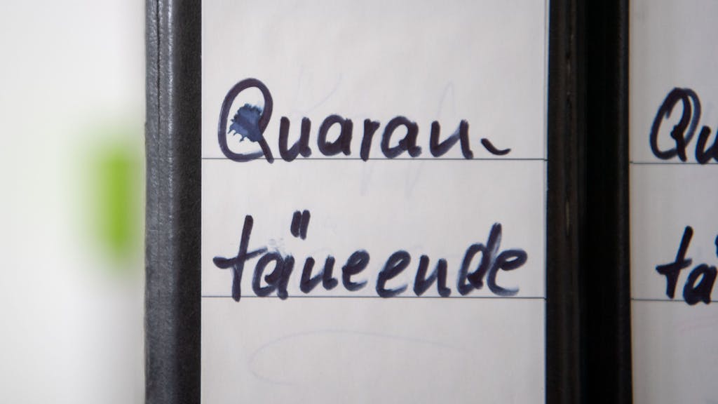 Ein Ordner mit der Aufschrift „Quarantäneende“ stehen auf einem Regal.