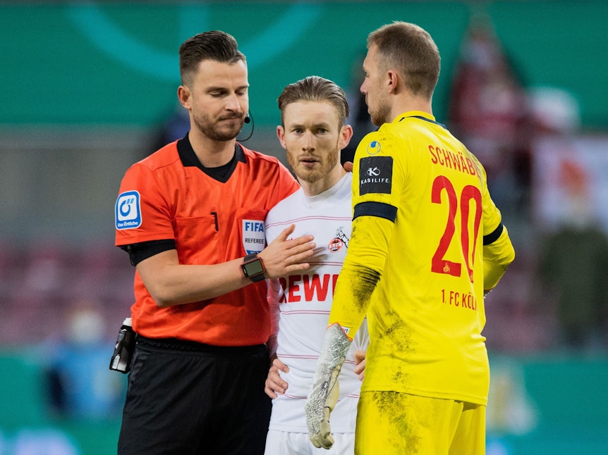 Schiedsrichter Daniel Schlager (l) tröstet Florian Kainz, der bei seinem Elfmeter den Ball zwei Mal berührt hatte, rechts steht Kölns Torwart Marvin Schwäbe.