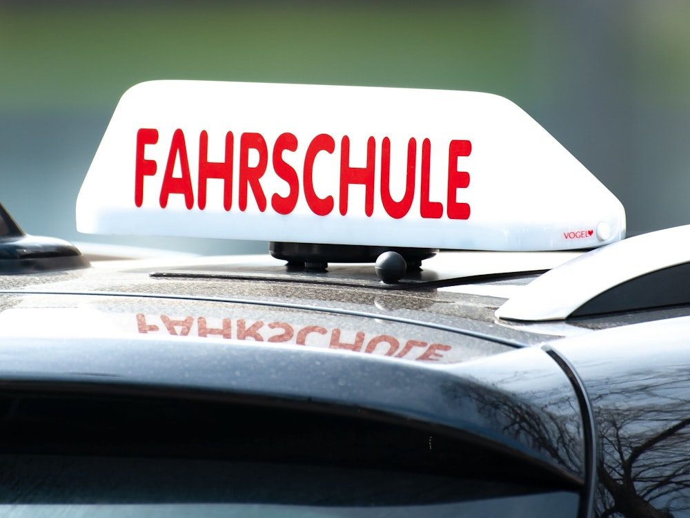 Ein Schild mit der Aufschrift „Fahrschule“ ist auf einem Fahrschulauto befestigt.