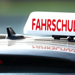 Ein Schild mit der Aufschrift „Fahrschule“ ist auf einem Fahrschulauto befestigt.