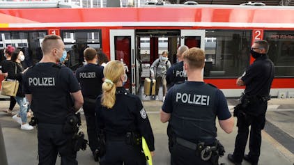 
Eine Beamtin und mehrere Beamte der Bundespolizei stehen im Bahnhof auf einem Gleis, an dem gerade eine Bahn angekommen ist.&nbsp;