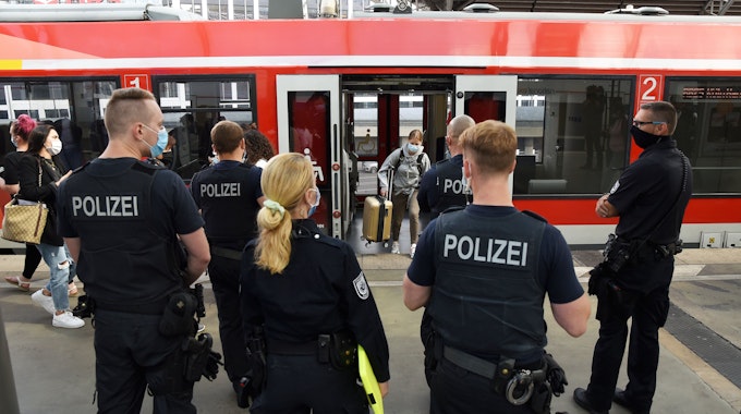 Beamte und Beamtinnen der Polizei und des Ordnungsamtes stehen im Kölner Hauptbahnhof.