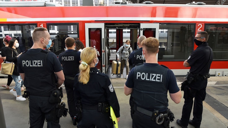 Beamte und Beamtinnen der Polizei und des Ordnungsamtes stehen im Kölner Hauptbahnhof.