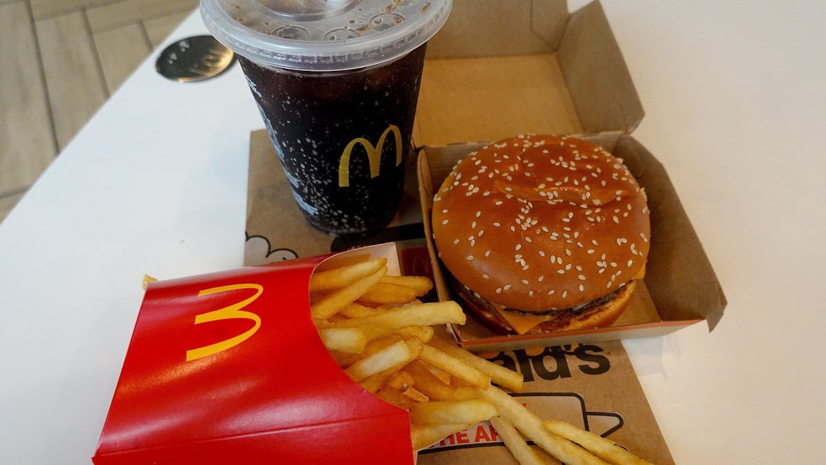 Ein Burger, eine Pommes und ein Getränk von McDonald's auf einem Tisch.