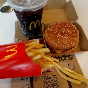 Ein Burger, eine Pommes und ein Getränk von McDonald's auf einem Tisch.
