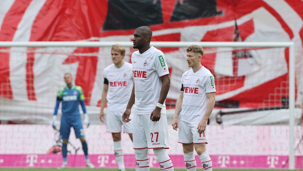 Anthony Modeste, Timo Hübers und Florian Kainz stehen im Spiel gegen den VfL Wolfsburg, als der 1. FC Köln die Teilnahme zur Conference League perfekt machte, auf dem Rasen