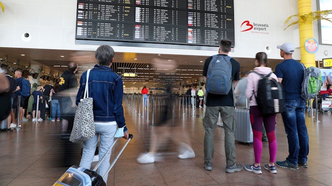 Reisende schauen in der Abflughalle des Brüsseler Flughafens in Zaventem auf die Anzeigetafel für den Abflug.