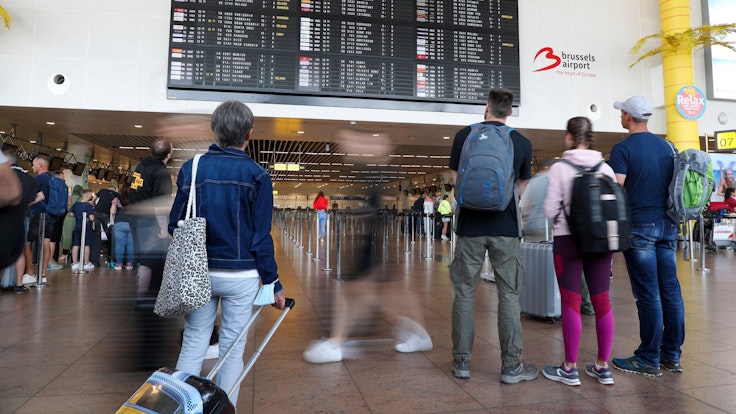 Reisende schauen in der Abflughalle des Brüsseler Flughafens in Zaventem auf die Anzeigetafel für den Abflug.