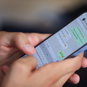 Ein junger Mann tippt auf einem Smartphone eine WhatsApp Nachricht.