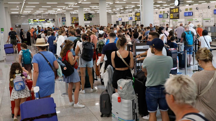 Reisende warten am Flughafen Palma de Mallorca an der Gepäckaufgabe.