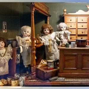 Puppen sind unter Sammlern und Sammlerinnen heiß begehrt. Das Symbolbild zeigt einen Puppen-Gemischtwarenladen aus dem 19. Jahrhundert in einer Vitrine des Puppenmuseums-Falkenstein.