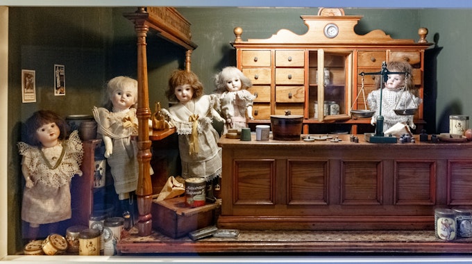 Puppen sind unter Sammlern und Sammlerinnen heiß begehrt. Das Symbolbild zeigt einen Puppen-Gemischtwarenladen aus dem 19. Jahrhundert in einer Vitrine des Puppenmuseums-Falkenstein.