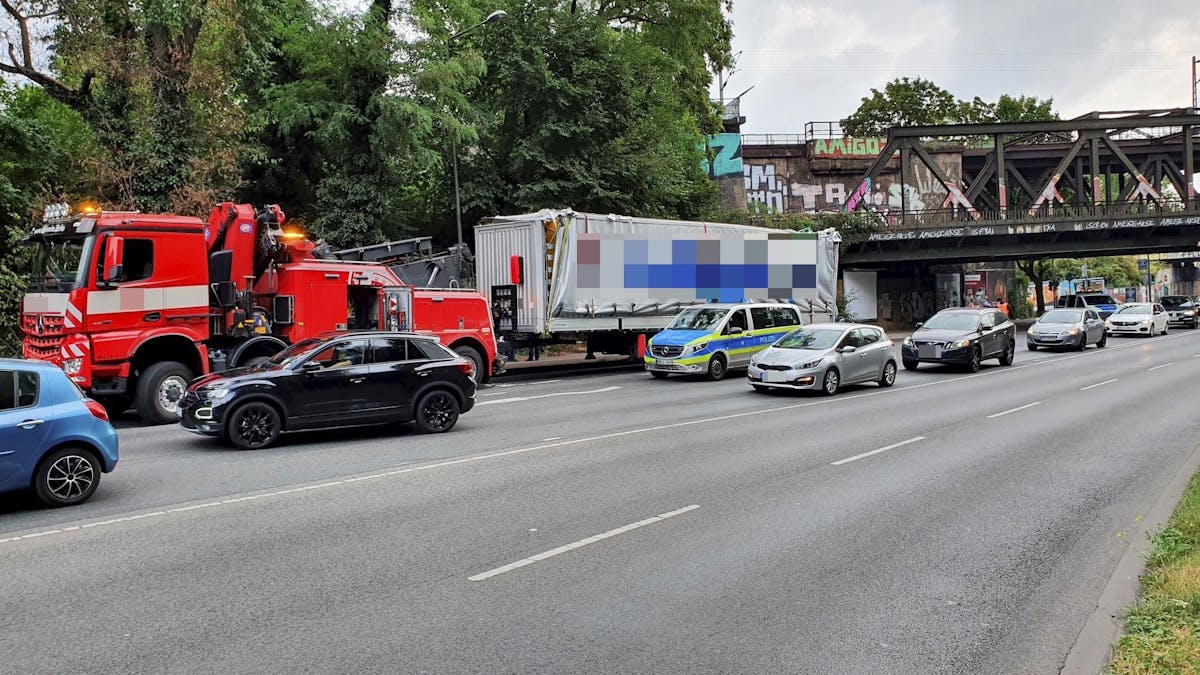 Ein beschädigter Lkw-Anhänger steht ein paar Meter hinter einer Eisenbahnbrücke, neben dem Anhänger steht ein Polizeifahrzeug.&nbsp;