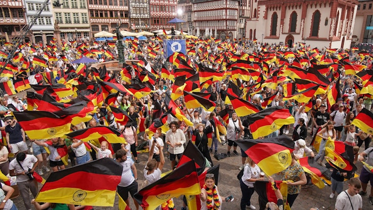 Zahlreiche Fans schwenken Deutschland-Flaggen beim Empfang der DFB-Auswahl in Frankfurt.