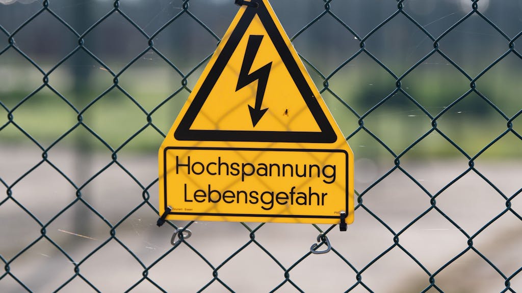 Ein Schild mit der Aufschrift „Hochspannung Lebensgefahr“ hängt an einem Zaun. In Levergusen-Opladen ist am Freitag der Strom ausgefallen.