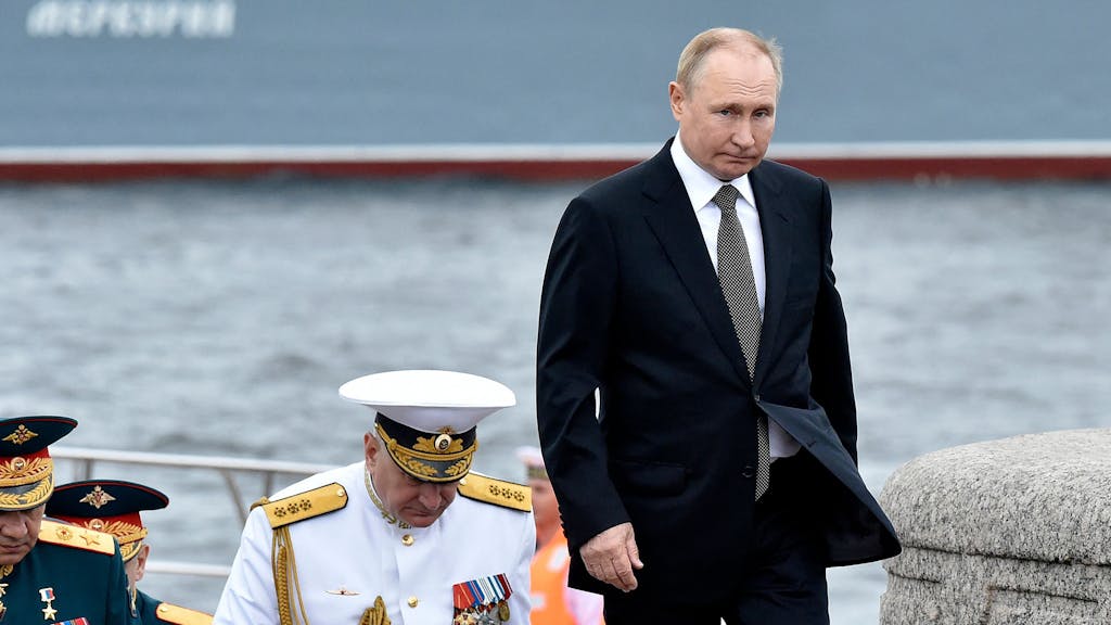 Russia's President Vladimir Putin (R) walks with Commander-in-Chief of the Russian Navy, Admiral Nikolai Yevmenov (C) as he takes part in the main naval parade marking Russian Navy Day, in St. Petersburg on July 31, 2022. (Photo by Olga MALTSEVA / AFP)