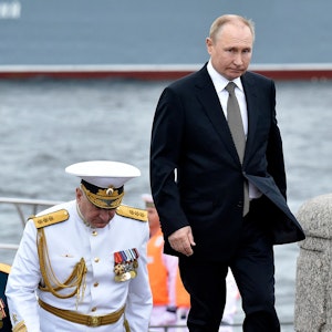 Russia's President Vladimir Putin (R) walks with Commander-in-Chief of the Russian Navy, Admiral Nikolai Yevmenov (C) as he takes part in the main naval parade marking Russian Navy Day, in St. Petersburg on July 31, 2022. (Photo by Olga MALTSEVA / AFP)