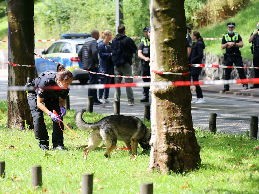 Eine Polizistin ist innerhalb einer Polizeiabsperrung mit einem Spürhund in Hamburg bei einem Einsatz.