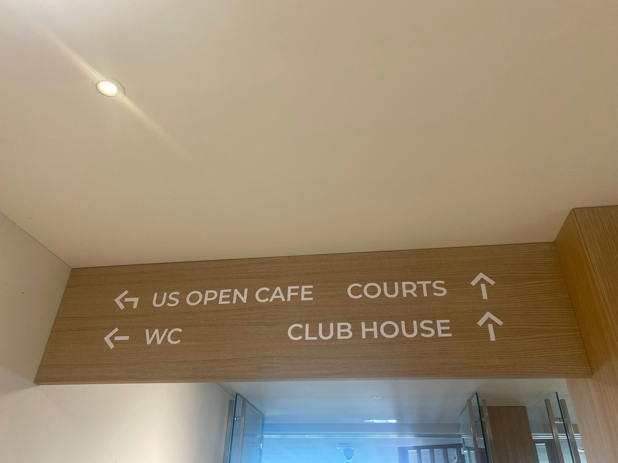 Schilder im Inneren des Sport Centers weisen den Weg. Der Gastronomiebetrieb heißt thematisch passend „US Open Cafe“. Fotografiert wurde das am 20. Juli 2022.
