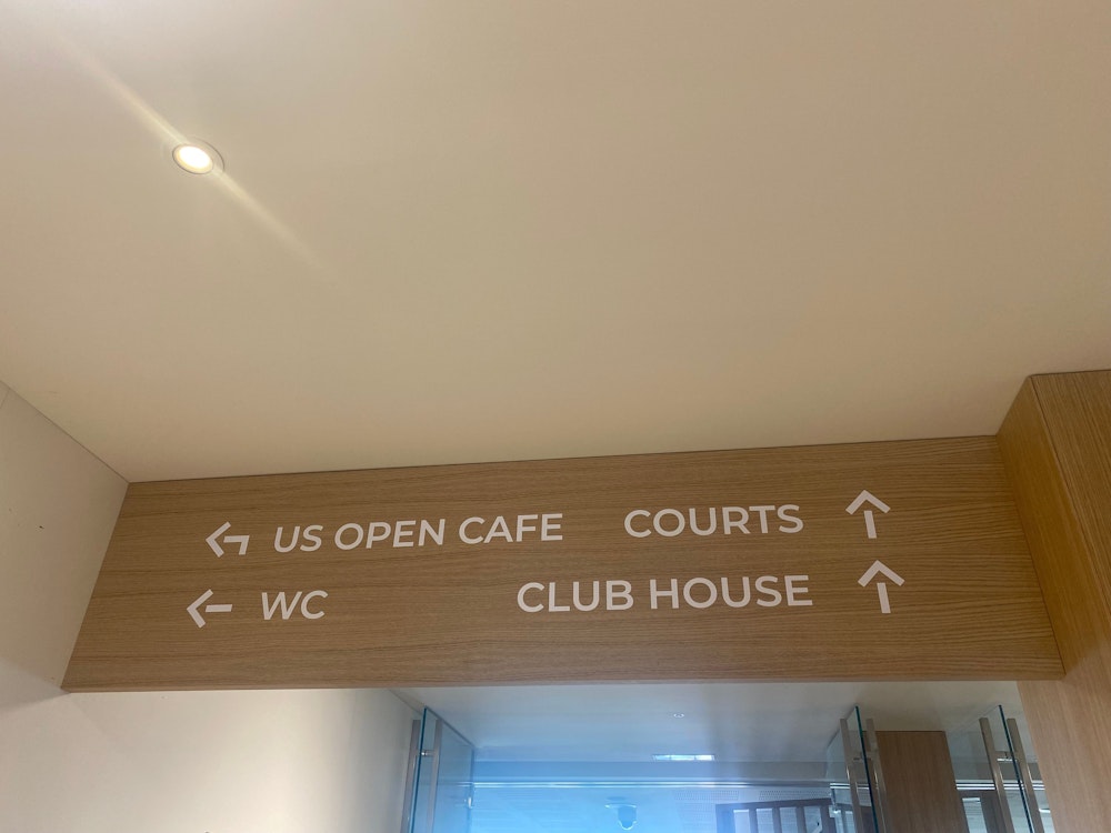 Schilder im Inneren des Sport Centers weisen den Weg. Der Gastronomiebetrieb heißt thematisch passend „US Open Cafe“. Fotografiert wurde das am 20. Juli 2022.