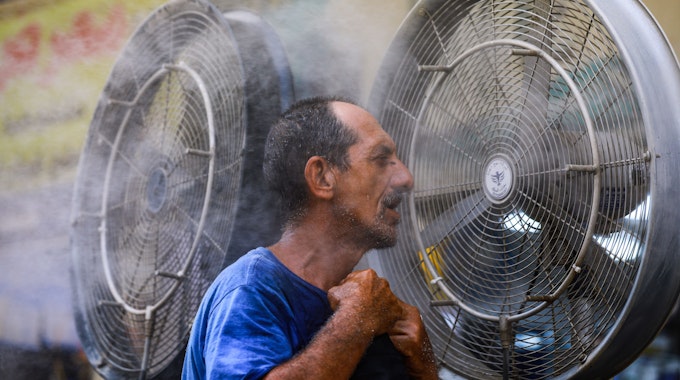 Ein Mann kühlt sich vor einem Ventilator ab, während im Irak eine Hitzewelle herrscht