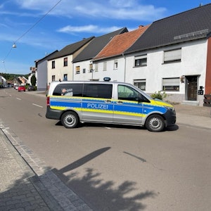 Auto der Polizei steht auf einer Straße in einem Wohngebiet.