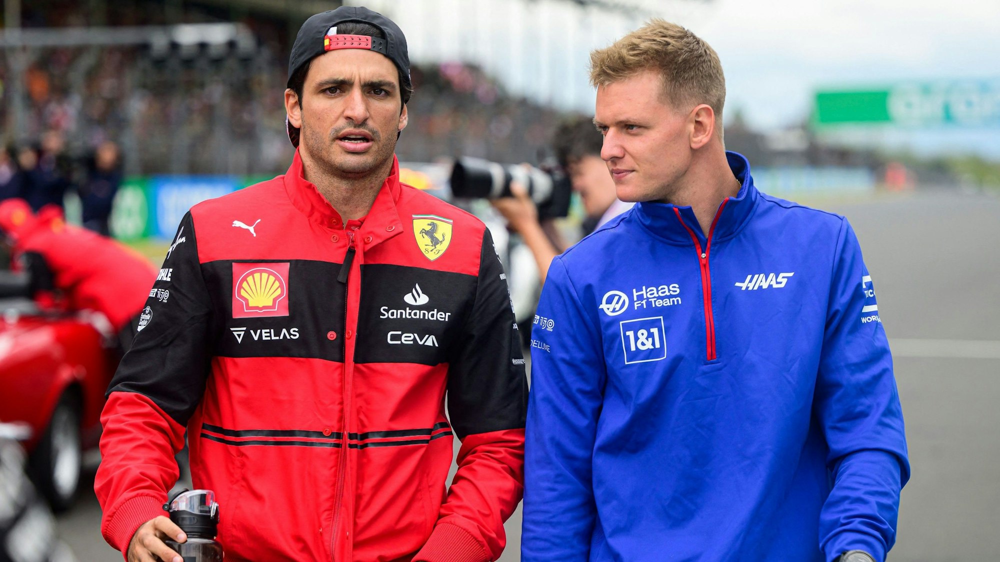 Mick Schumacher geht beim Renn-Wochenende der Formel 1 mit Ferrari-Pilot Carlos Sainz durch die Boxengasse.