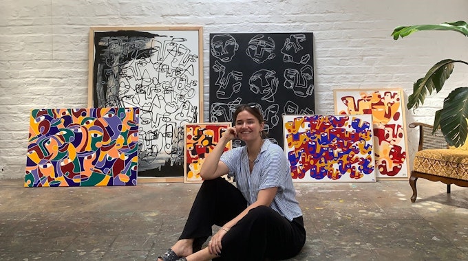 Hanna Hodler sitzt in ihrem Atelier auf dem Boden vor einigen ihrer Bilder.