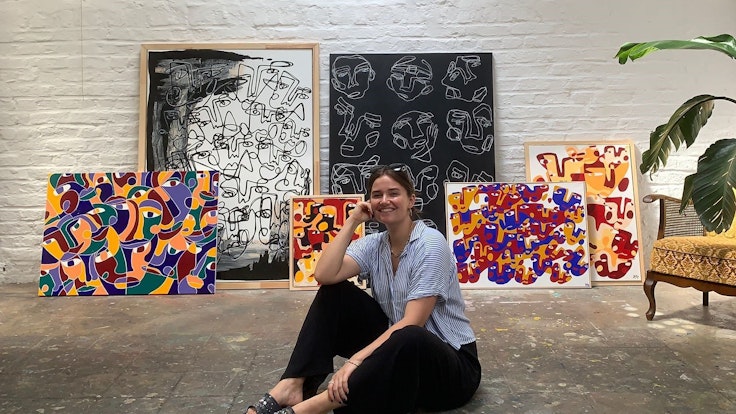 Hanna Hodler sitzt in ihrem Atelier auf dem Boden vor einigen ihrer Bilder.