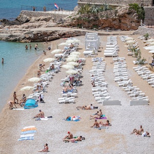 Touristinnen und Touristen entspannen am Strand von Dubrovnik (Kroatien).
