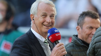 Rainer Bonhof, Vize-Präsident von Borussia Mönchengladbach im Interview mit dem TV-Sender Sky. Dieses Foto entstand vor dem Spiel gegen den 1. FC Köln am 16. April 2022. Bonhof hält ein Mikrofon in der rechten Hand und lächelt.