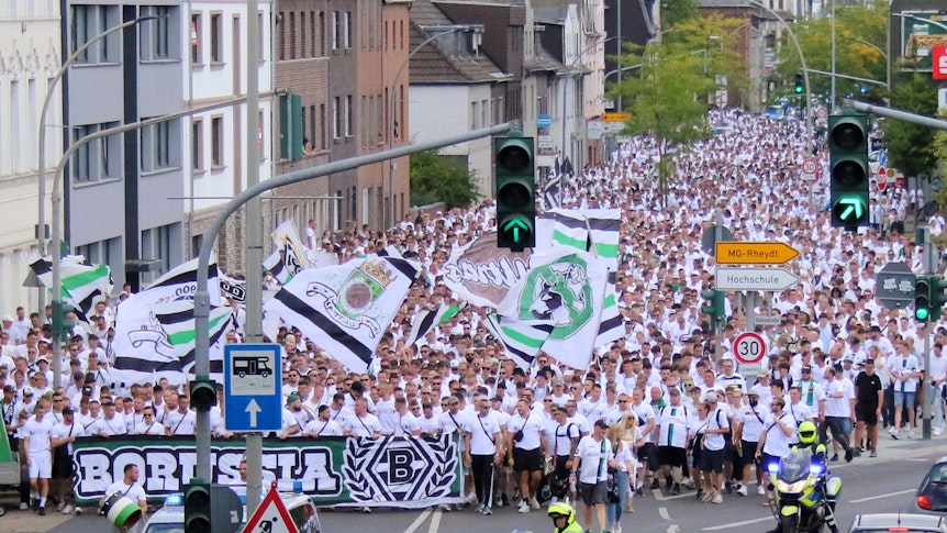 Tausende Menschen haben am Marsch der aktiven Fanszene von Borussia Mönchengladbach vor dem Bundesliga-Heimspiel am 6. August 2022 gegen die TSG Hoffenheim teilgenommen. Die Polizei regelt den Straßenverkehr.