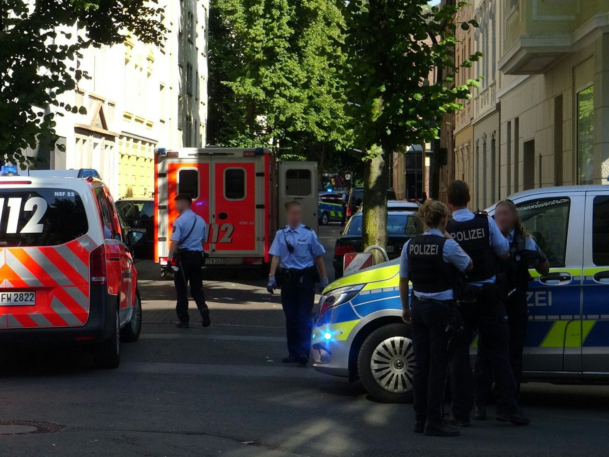 Einsatzfahrzeuge von Polizei und Rettungsdienst sowie mehrere Einsatzkräfte stehen in einer Straße.