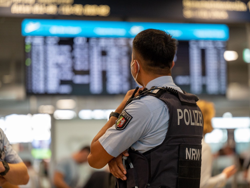 Ein Bundespolizist steht vor einer Anzeigetafel im Flughafen Köln/Bonn.