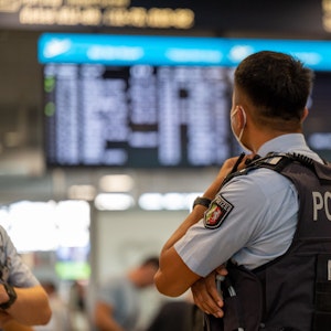 Ein Bundespolizist steht vor einer Anzeigetafel im Flughafen Köln/Bonn.