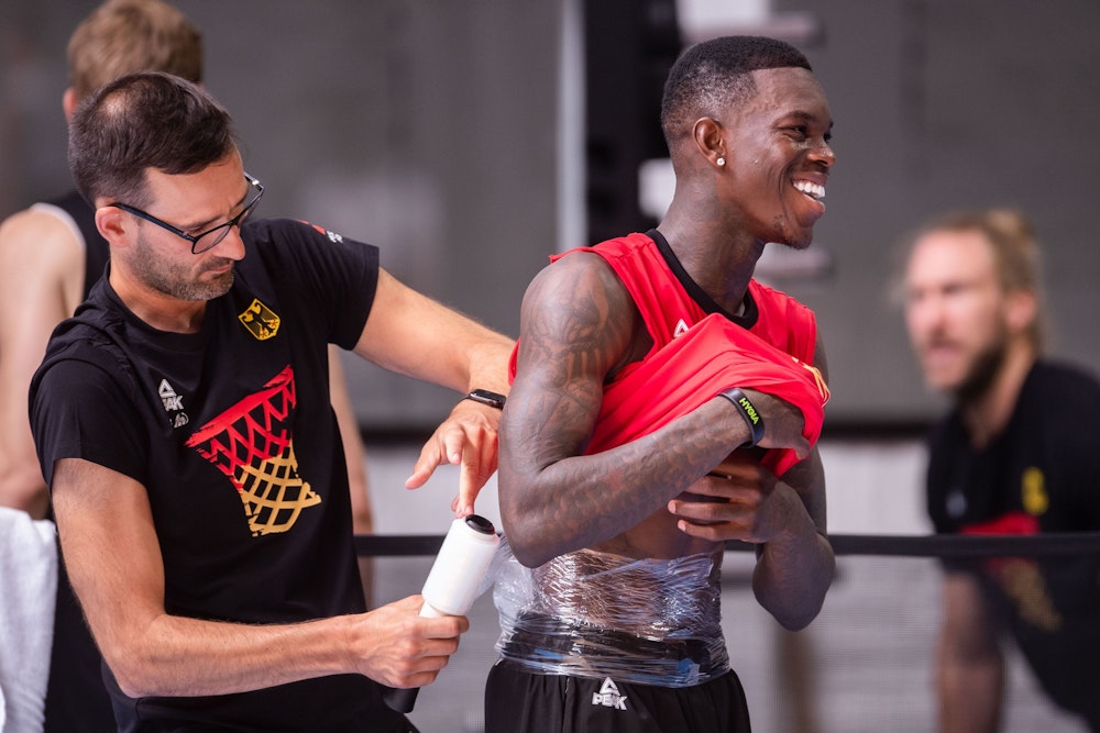 Dennis Schröder (r) lässt sich nach dem Training der Basketball-Nationalmannschaft einen Eisbeutel am Rücken befestigen. Die Mannschaft bereitet sich auf die Europameisterschaft vor, die im September ausgetragen wird.