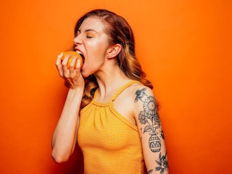 Eine junge Frau beißt auf diesem undatierten Symbolfoto genüsslich in ein Stück Obst.